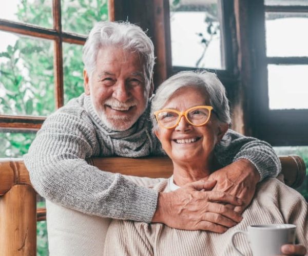 Portrait of couple of two happy and healthy seniors old people smiling and looking at the camera. Close up of mature grandparents enjoying and having fun together at home indoor.